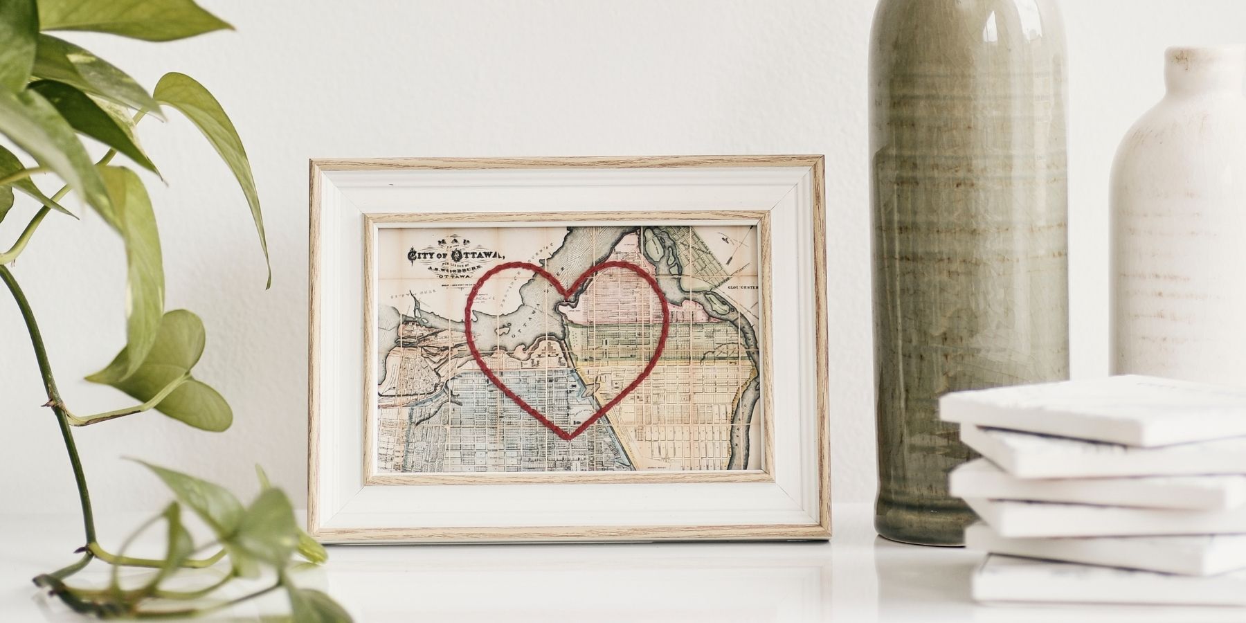 A vintage map of Ottawa with a red embroidered heart over the map in a white frame. This piece made by Sadie & June is part of a curated selection of Canadian made gifts at boogie + birdie in Ottawa.